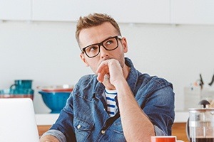 Man with glasses at desk with laptop