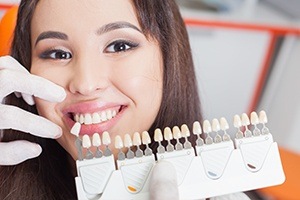 Woman's smile compared with tooth color chart