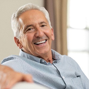 A closeup of an older man smiling while sitting on a couch