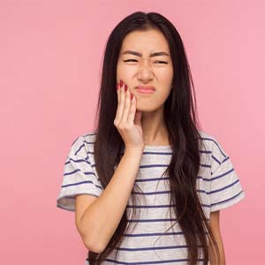 Woman with a toothache in Dallas holding her cheek