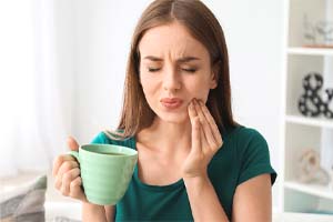 Woman with a dental emergency in Dallas holding a mug