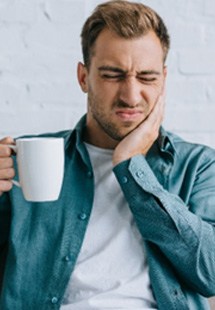 Closeup of man holding cheek due to tooth sensitivity