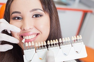 Woman's smile compared with tooth color chart