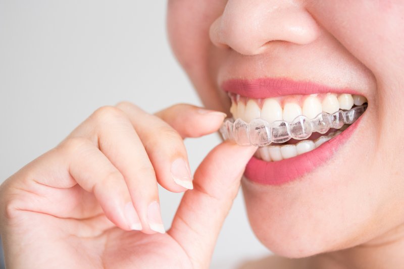 an up-close view of a person inserting a clear aligner after having their Invisalign questions in Dallas answered
