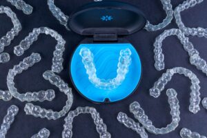 Birds eye view of many Invisalign trays and container on a black background