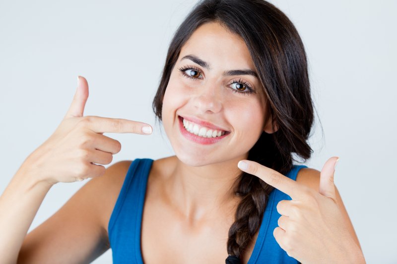 a young girl pointing to her smile after seeing her cosmetic dentist in Lakewood