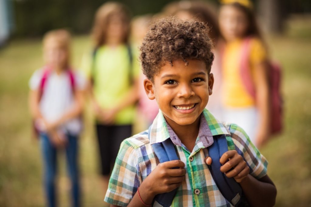 Young boy smiling while heading back to school with friends