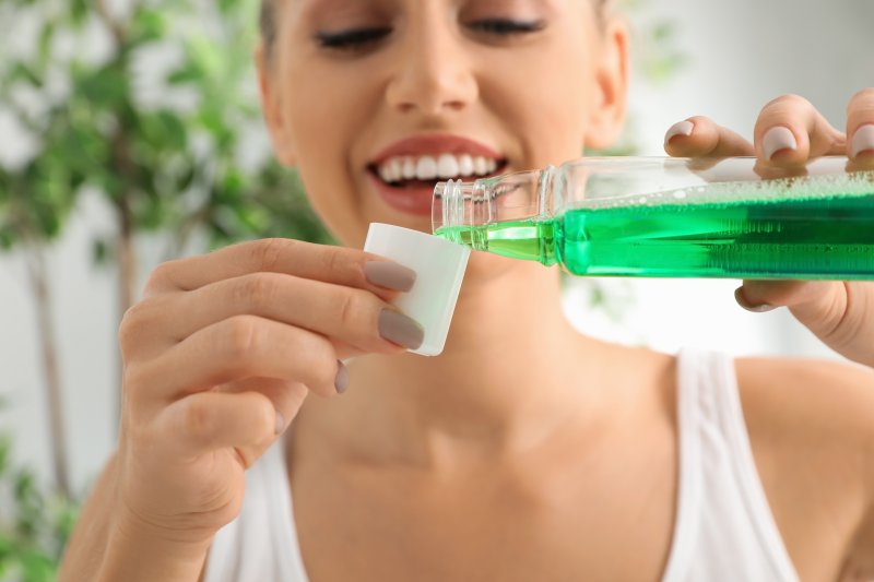 Woman smiling while pouring mouthwash into cap