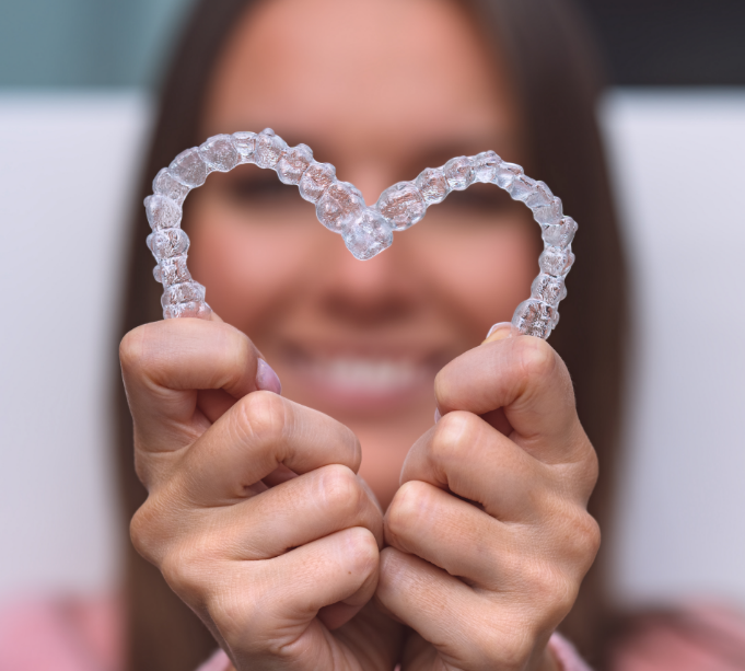 Woman holding clear aligners in heart shape